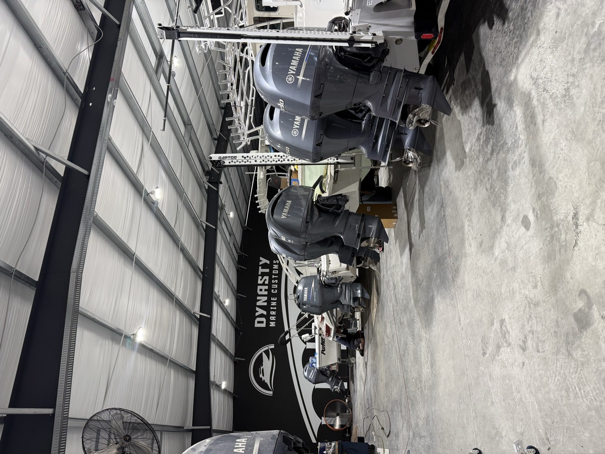 Row of outboard-powered boats in for service inside the Dynasty Marine Customs shop