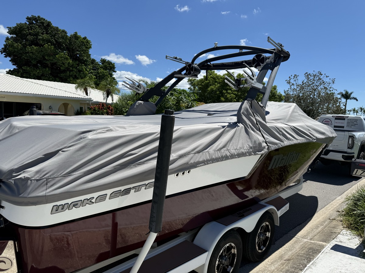 Custom cover fitted over a wake boat with a tower, on the trailer