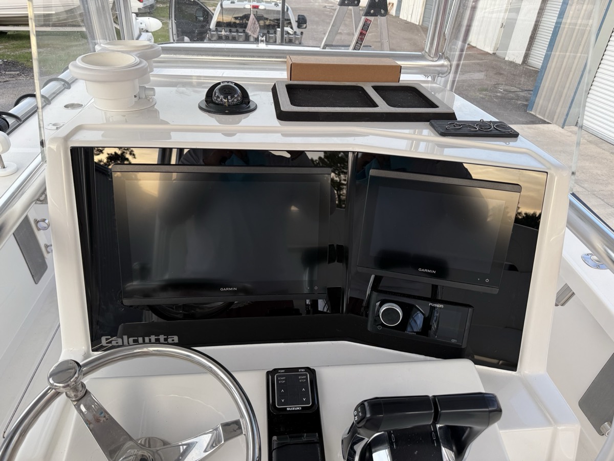 Custom acrylic dash panel with flush-mounted Garmin screens and switch bank on a Calcutta center console
